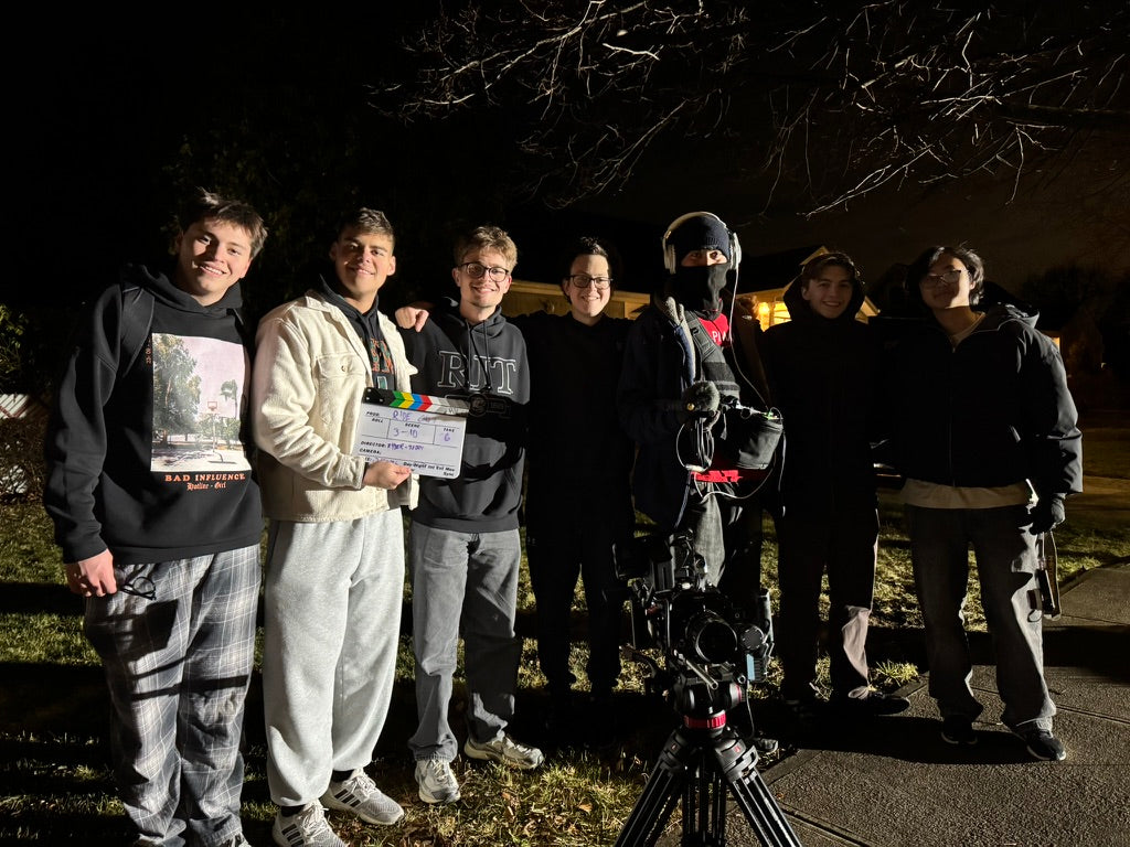 The Ride Out crew gathered around a cinema camera and slate outdoors at night.